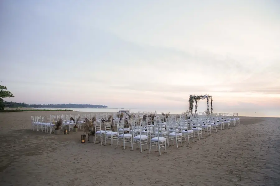 Beach ceremony set with chiavari chairs on open sand at dusk